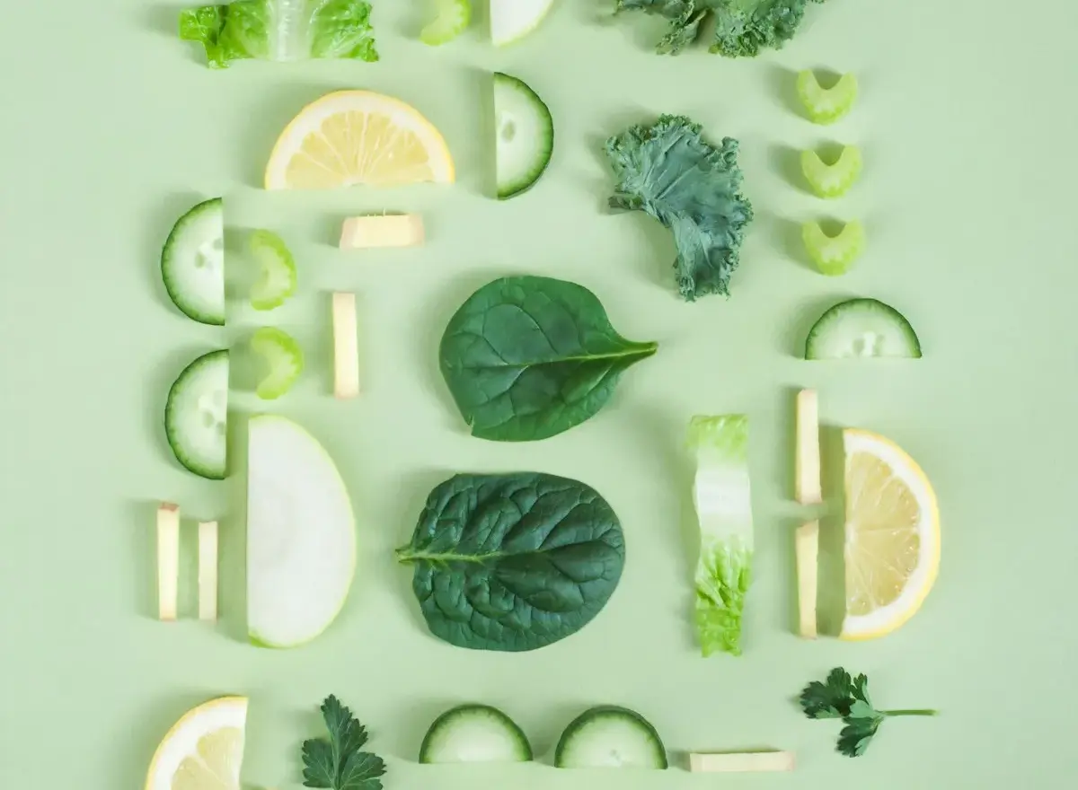 Feuilles d'&eacute;pinard, concombre, c&eacute;leri et rondelles de citron dispos&eacute;s en damier sur fond vert d'eau.